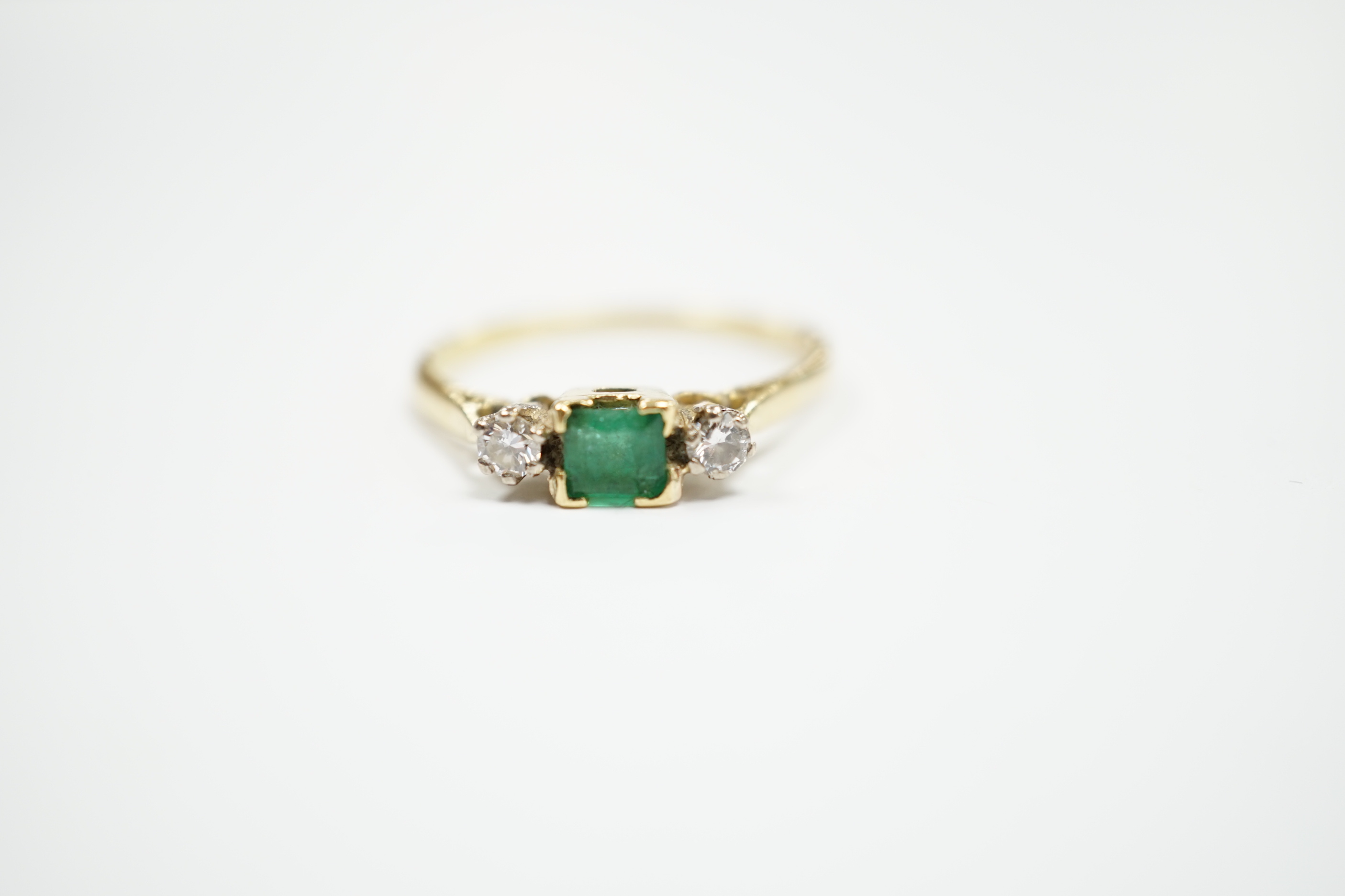 An 18ct and plat, single stone emerald and two stone diamond set ring, size Q/R, gross weight 2.6 grams.